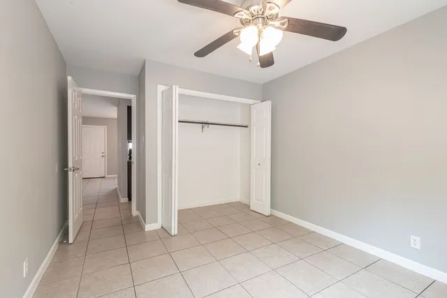 an empty room with closet and a chandelier fan