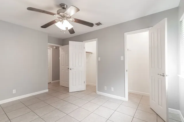 wooden floor in an empty room with a chandelier fan