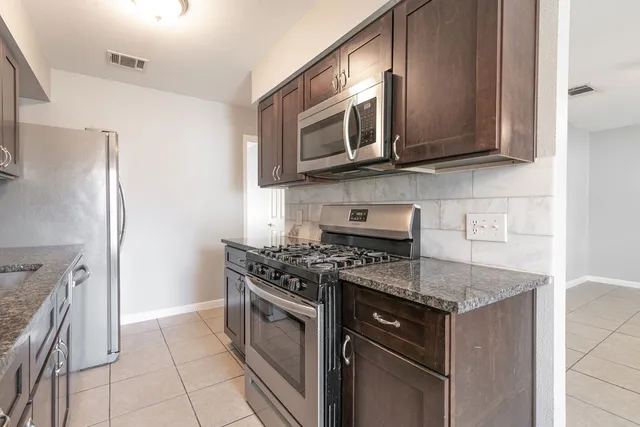 a kitchen with stainless steel appliances granite countertop a stove a microwave and a refrigerator