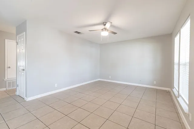 an empty room with windows and chandelier fan