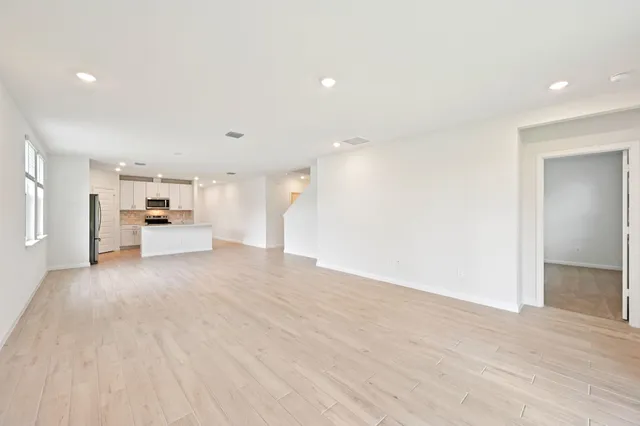 a view of kitchen with kitchen island a sink wooden floor and a large window
