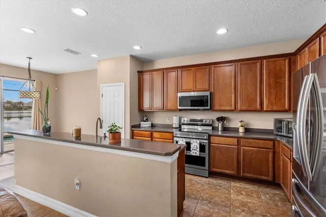 a kitchen with stainless steel appliances a sink a stove a refrigerator cabinets and a window