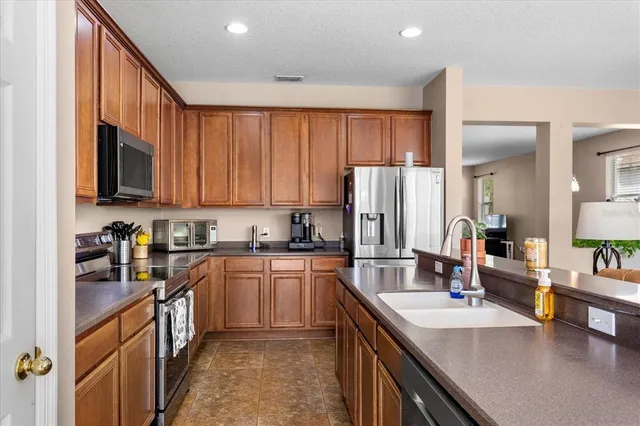 a kitchen with stainless steel appliances granite countertop a sink stove refrigerator and cabinets