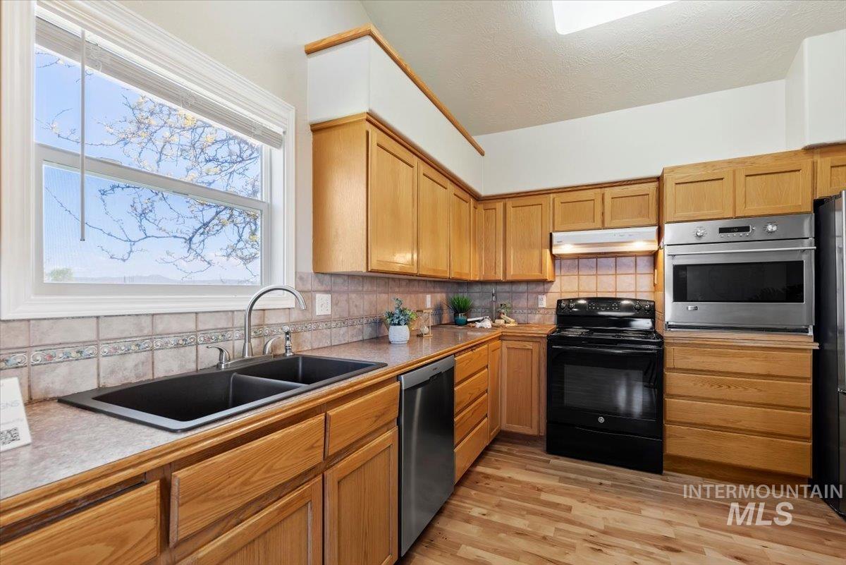 147 East Indian Crk Road Boise, ID 83716 - Photo 12 of 43 Light wood cabinetry with a black double-basin sink and stainless steel appliances