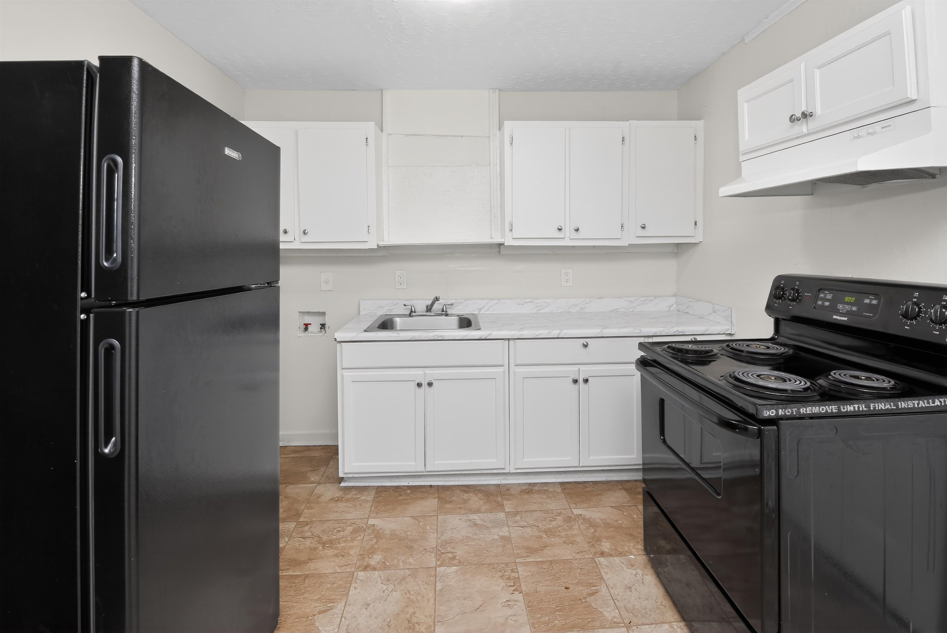 4838 Manson Road Memphis, TN 38109 - Photo 17 of 28 Kitchen featuring black appliances, white cabinetry, a stainless steel sink, and light-toned flooring