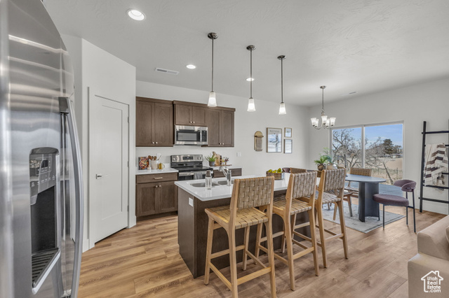 155 East 360th Street East, Unit 10B Fillmore, UT 84631 - Photo 9 of 43 Kitchen featuring hanging light fixtures, stainless steel appliances, an inviting chandelier, an island with sink, and dark brown cabinets