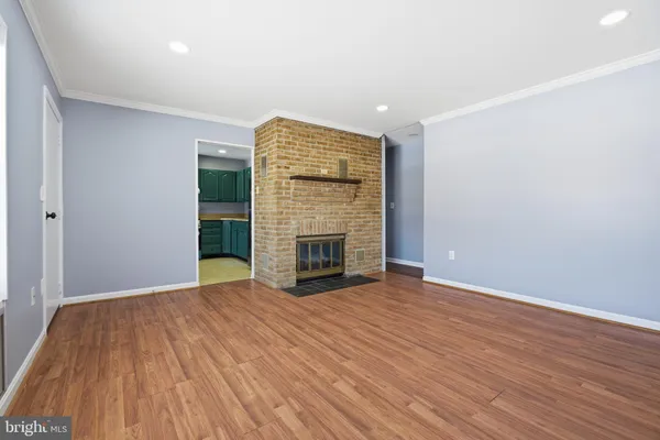 a view of an empty room with wooden floor fireplace and a window