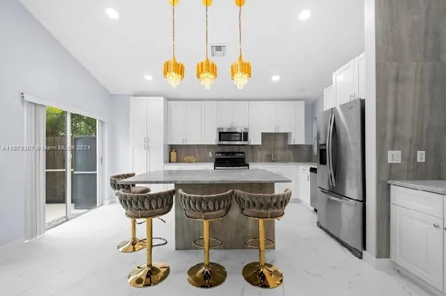 a kitchen with stainless steel appliances granite countertop a sink a stove a refrigerator and a dining table with wooden floor