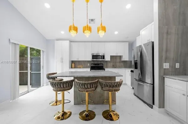 a kitchen with stainless steel appliances granite countertop a sink a stove a refrigerator and a dining table with wooden floor