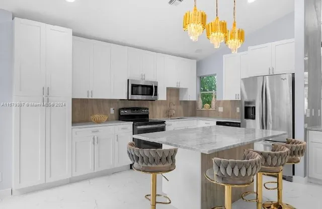 a kitchen with stainless steel appliances granite countertop a stove a refrigerator a kitchen island a stove a sink dishwasher and white cabinets with wooden floor