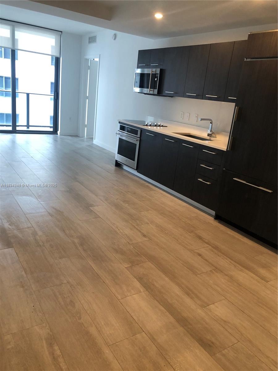 55 Southwest 9th Street, Unit 3009 Miami, FL 33130 - Photo 8 of 15 a kitchen with stainless steel appliances wooden cabinets and wooden floor