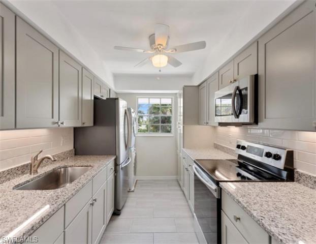 4900 Biscayne Drive, Unit 23 Naples, FL 34112 - Photo 1 of 21 Kitchen featuring gray cabinets, appliances with stainless steel finishes, sink, backsplash, and light stone countertops