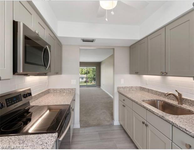 4900 Biscayne Drive, Unit 23 Naples, FL 34112 - Photo 2 of 21 Kitchen featuring gray cabinetry, sink, decorative backsplash, and stainless steel appliances