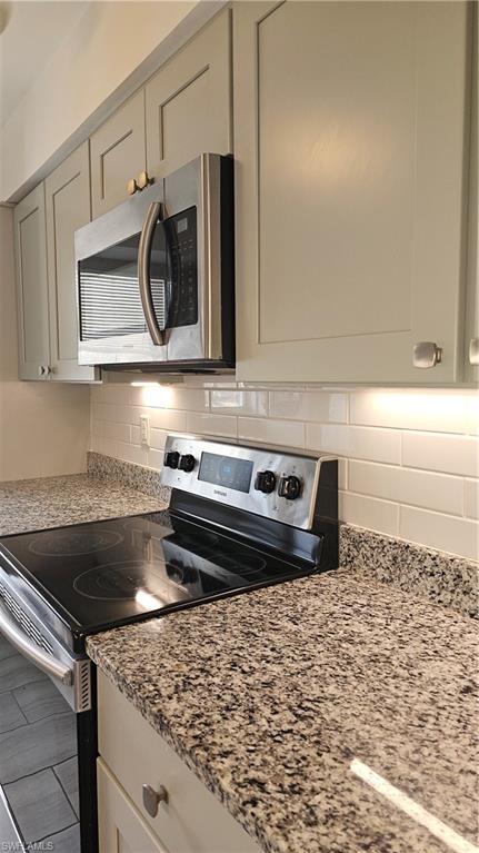4900 Biscayne Drive, Unit 23 Naples, FL 34112 - Photo 4 of 21 Kitchen with backsplash, light stone countertops, and stove