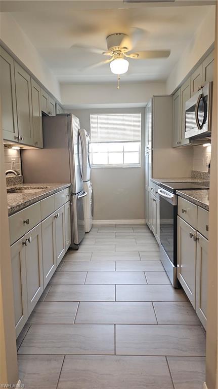 4900 Biscayne Drive, Unit 23 Naples, FL 34112 - Photo 5 of 21 Kitchen with sink, stove, backsplash, dark stone countertops, and stacked washer / drying machine