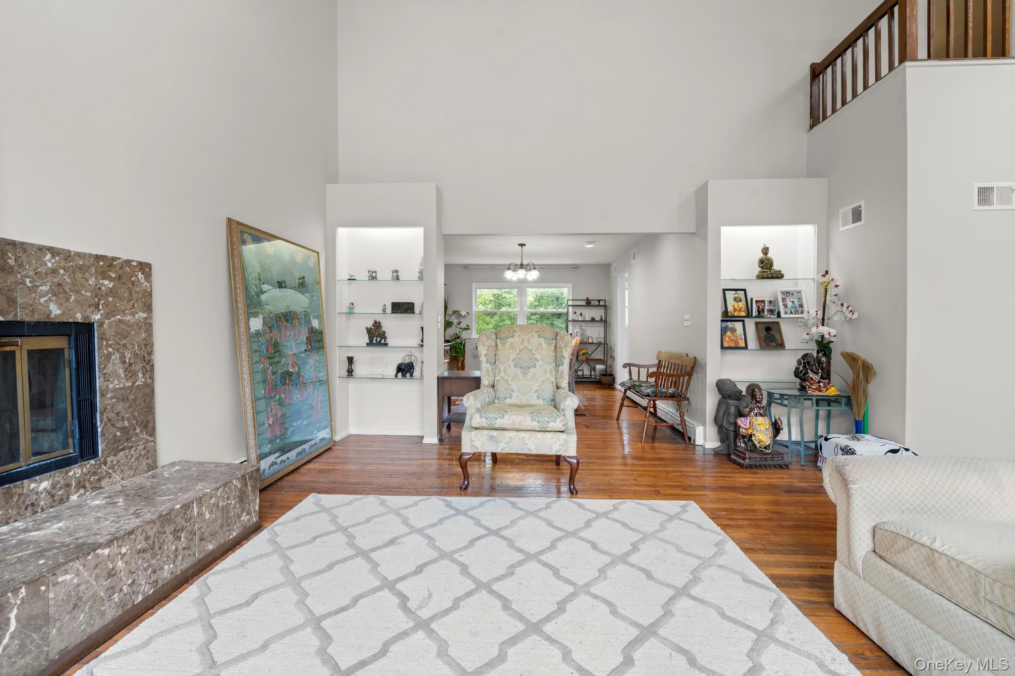 513 Bedford Road Armonk, NY 10504 - Photo 7 of 38 Living room featuring a towering ceiling, wood finished floors, a chandelier, and a high end fireplace