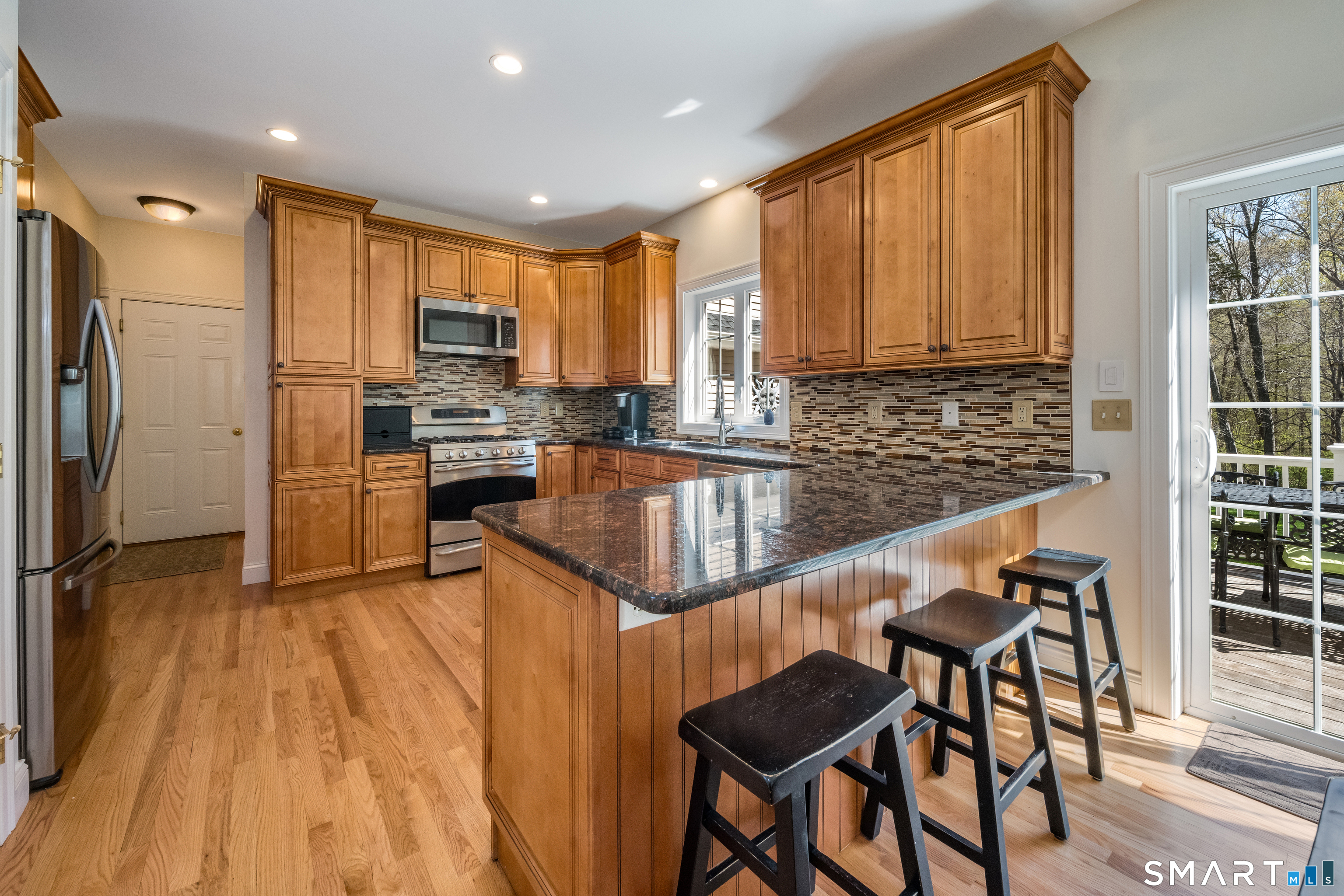 463 Tanner Marsh Road Guilford, CT 06437 - Photo 7 of 40 a kitchen with stainless steel appliances granite countertop a refrigerator a stove a sink dishwasher and white cabinets with wooden floor