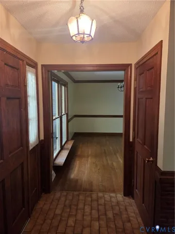 a view of an empty room with wooden floor and chandelier