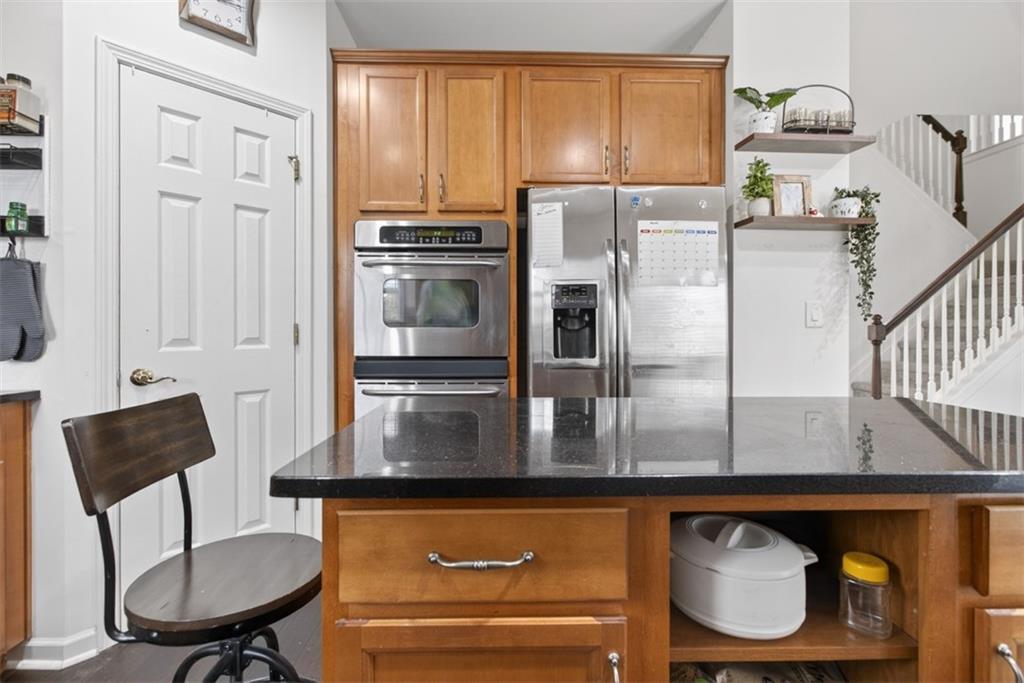 3210 Warbler Way Cumming, GA 30041 - Photo 17 of 45 a kitchen with stainless steel appliances granite countertop a refrigerator a stove a sink and a dining table with wooden cabinet