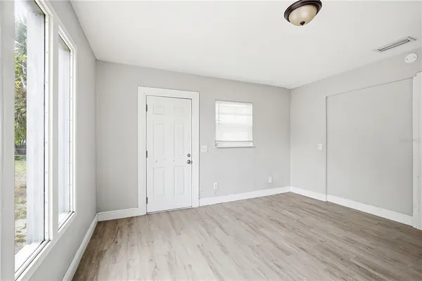 a view of an empty room with wooden floor and a window