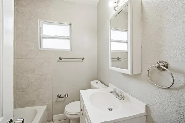 a bathroom with a toilet sink vanity and mirror