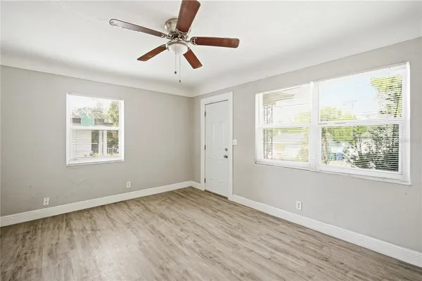 a view of empty room with wooden floor and fan
