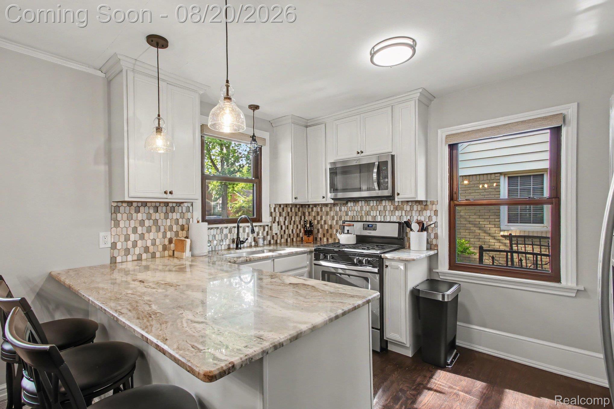 4098 Wakefield Road Berkley, MI 48072 - Photo 13 of 49 Kitchen featuring white cabinetry, patterned tile backsplash, stainless steel appliances, pendant lighting, and a breakfast bar with stone countertops