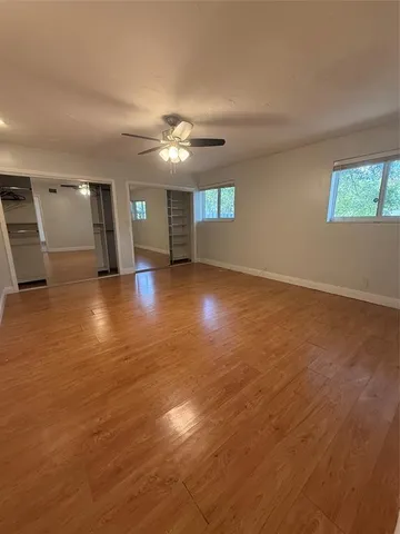 an empty room with wooden floor chandelier and windows