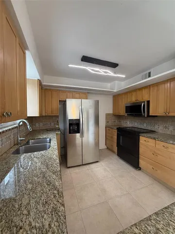 a large kitchen with granite countertop a sink and white cabinets