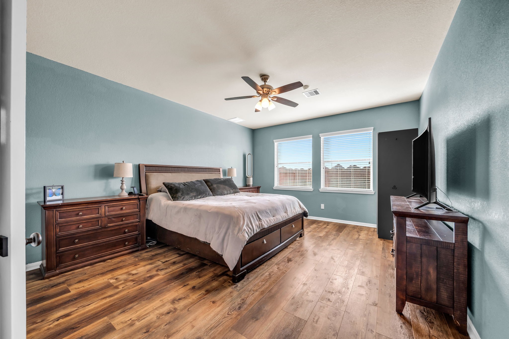 14212 Portrait Court Houston, TX 77045 - Photo 11 of 27 Spacious primary bedroom with abundant natural light, elegant floors, and a ceiling fan for added comfort.