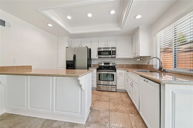 a kitchen with granite countertop a sink a counter top space stainless steel appliances and cabinets