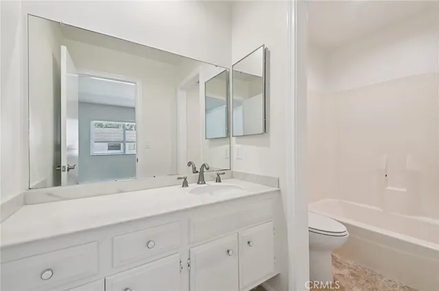 a bathroom with a granite countertop sink a toilet and a bathtub