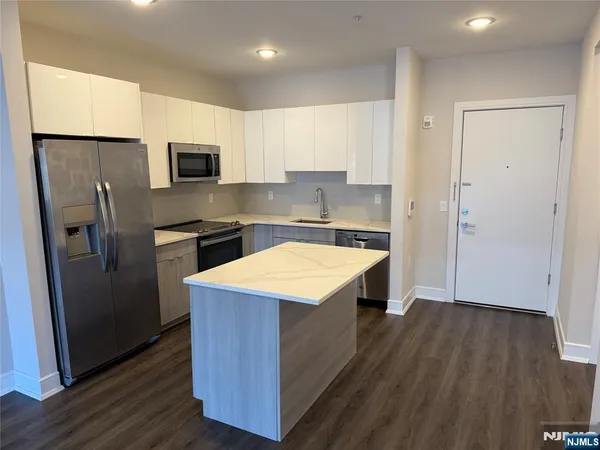 a kitchen with stainless steel appliances a sink a refrigerator and wooden floor