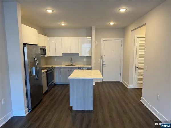 a kitchen with kitchen island wooden floors appliances and cabinets