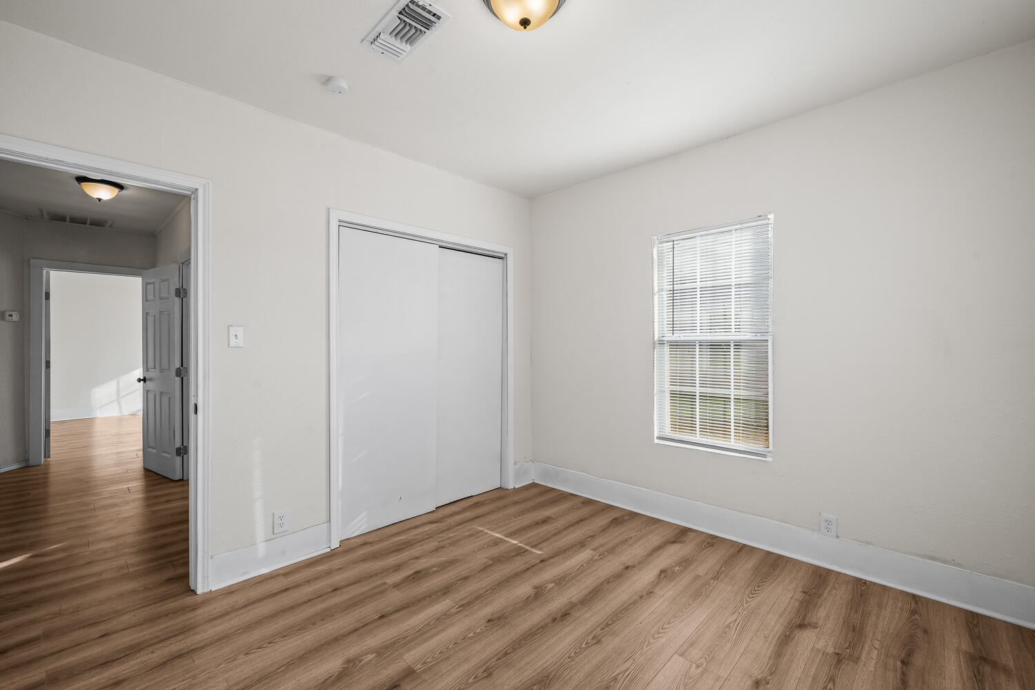 620 South 11th Street Slaton, TX 79364 - Photo 16 of 22 an empty room with wooden floor and windows