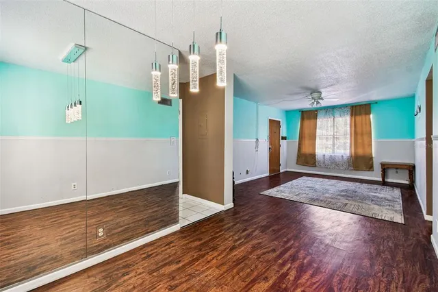a view of empty room with wooden floor and fan
