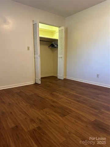 a view of an empty room with wooden floor and closet