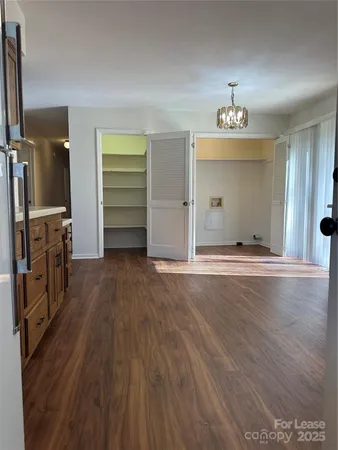 an empty room with wooden floor closet and windows