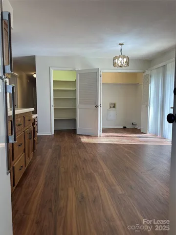 an empty room with wooden floor closet and windows