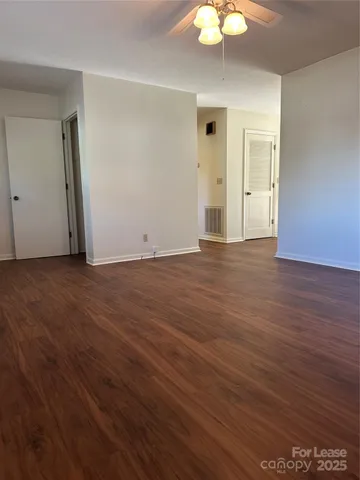 an empty room with wooden floor and chandelier fan