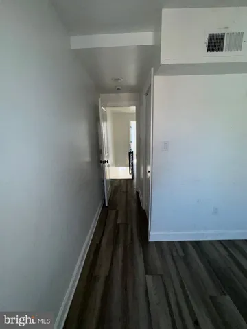 a view of a hallway with wooden floor and a bathroom