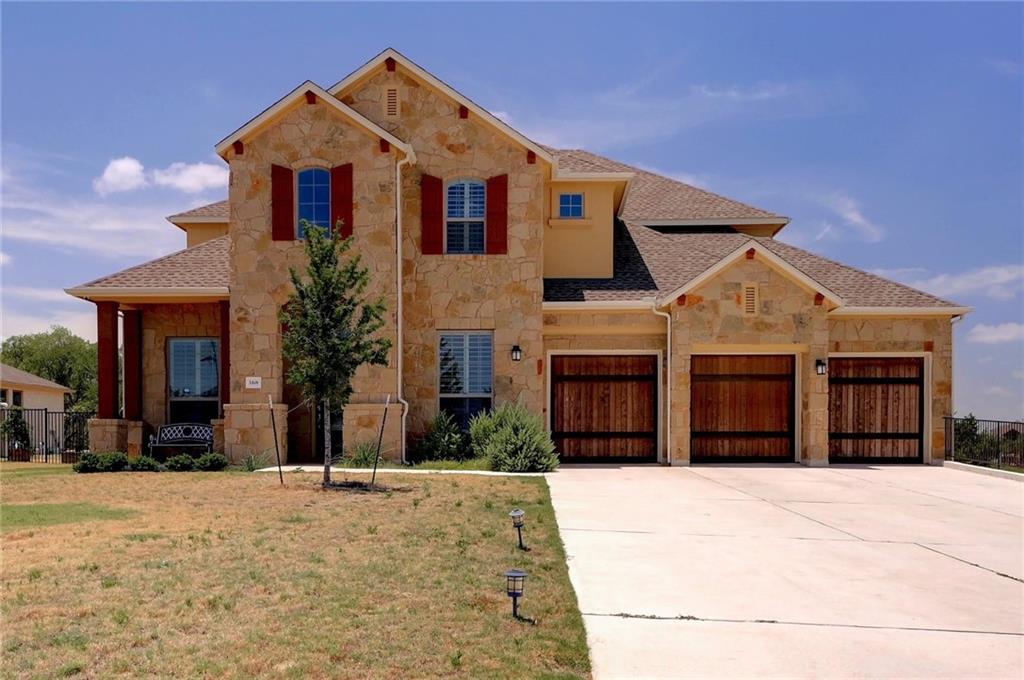 Stone and stucco exterior featuring a multi-gable roofline and a three-car garage with wood-finish doors