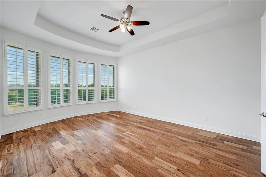 168 Raton Pass Dripping Springs, TX 78620 - Photo 13 of 20 Spacious room featuring wood-finish flooring, a tray ceiling, and a ceiling fan with light fixture