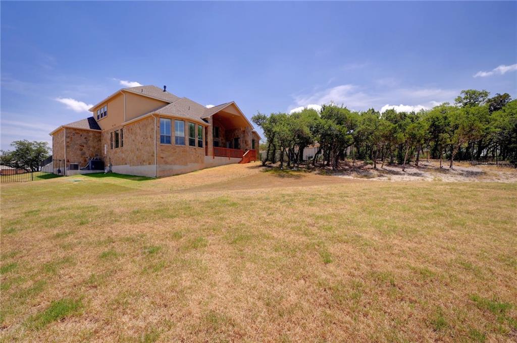 168 Raton Pass Dripping Springs, TX 78620 - Photo 19 of 20 Stone and stucco exterior with multiple windows and a covered outdoor living area featuring a wood deck