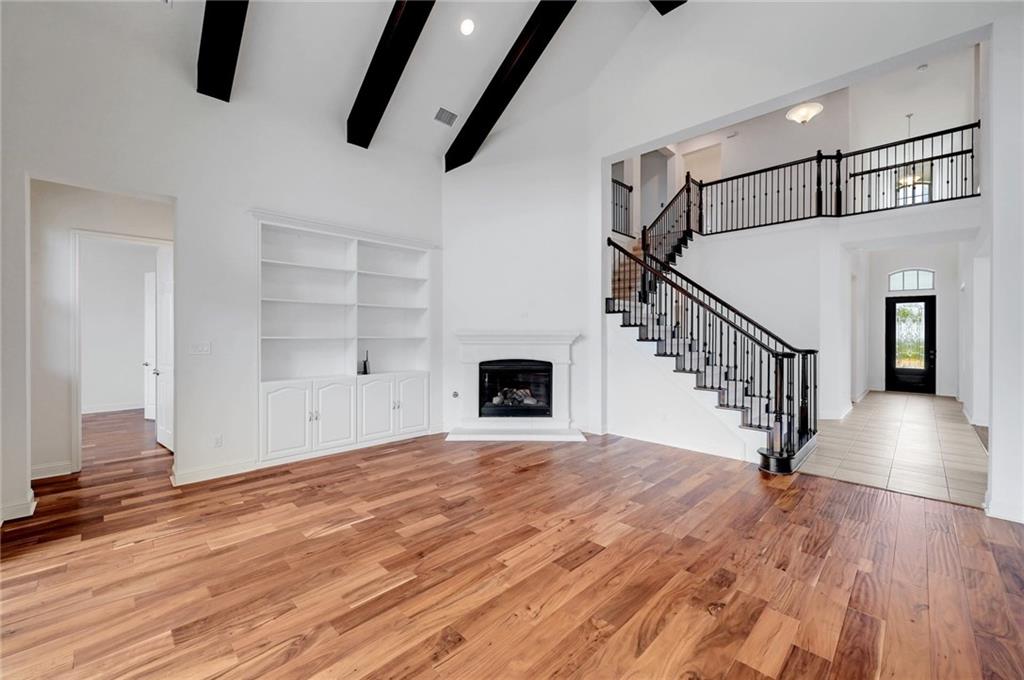 168 Raton Pass Dripping Springs, TX 78620 - Photo 6 of 20 Spacious living area featuring high vaulted ceilings with exposed dark wood beams, wood-finish flooring, and a corner fireplace with a white mantel