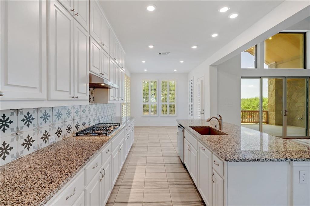 168 Raton Pass Dripping Springs, TX 78620 - Photo 10 of 20 Galley kitchen featuring extensive white cabinetry, granite countertops, a gas cooktop, tile backsplash with decorative accents, and recessed lighting