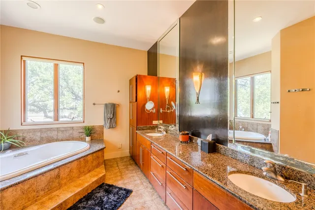 a bathroom with a granite countertop tub sink and mirror