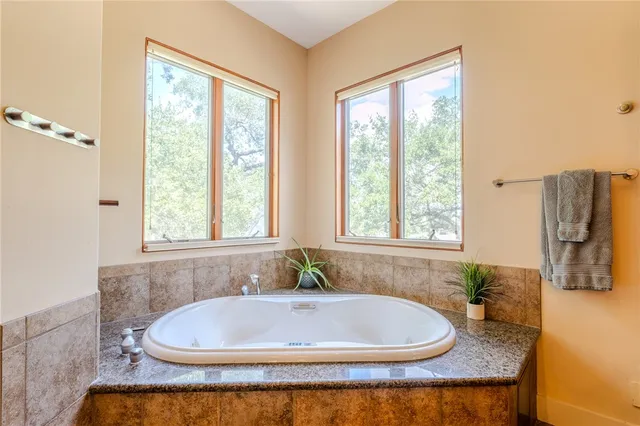 a bathroom with a granite countertop tub and a window