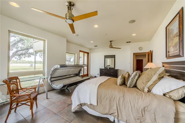 a bedroom with a bed a chair and potted plant with the dresser