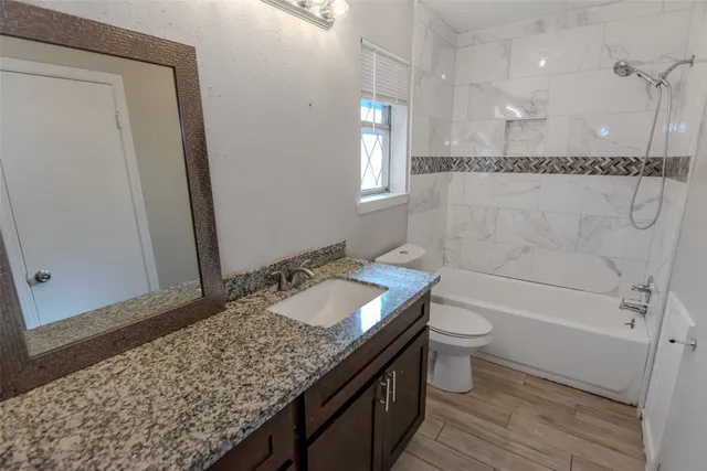a bathroom with a granite countertop sink toilet and shower